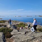 Ihmisiä kalliorannalla Saaristomerellä keräämässä roskia.